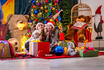 Two girls celebrate Christmas with gifts and a decorated tree