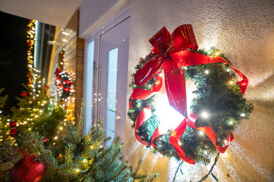 Festive Christmas wreath with red bow and lights on a front door