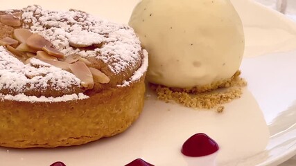 Gourmet almond tart with vanilla ice cream and red coulis, elegantly plated for a sophisticated dessert experience in the English countryside restaurant - Powered by Adobe