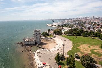 Aerial drone shot of Belem Tower historic fortress on Tagus River in Lisbon, with tourists visiting and exploring the iconic monument