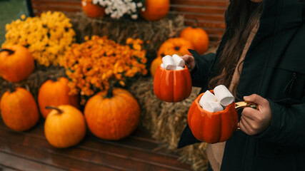 Cozy autumn scene with pumpkin mugs filled with marshmallows and fall decor