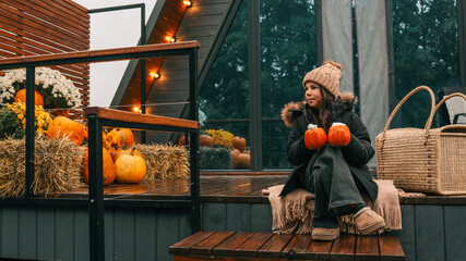 Young girl enjoying autumn with pumpkins and warm drinks on a cozy porch