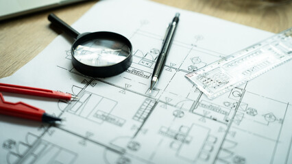 A drawing of a house with a magnifying glass and a pencil on top of it. The drawing is in black and white and the pencil is red
