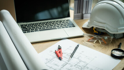 A laptop is placed on a table with a pair of red calipers and safety glasses. The scene suggests that someone is working on a project that requires precise measurements and safety precautions