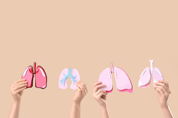 Female doctor's hands with different paper lungs on beige background, closeup