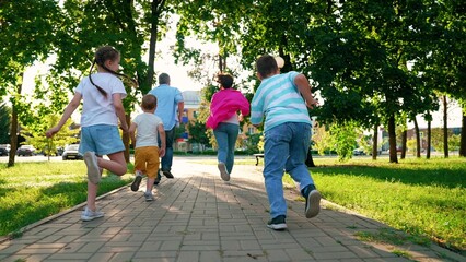 Dad mom sons kids have fun run along city street. Concept of raising children. Family in city park. Parents children boys play running in city park summer. Happy family. Happy people mother father son