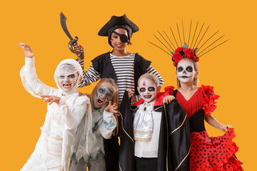 Group of children dressed for Halloween on yellow background