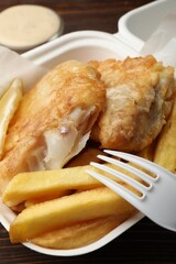 British Traditional Fish and chips with sauce on wooden table, closeup