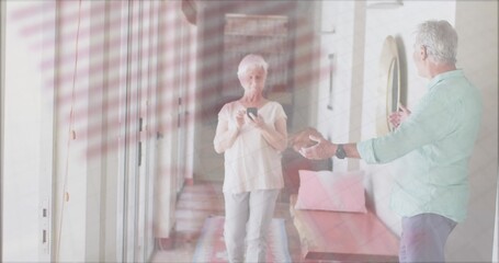 Standing couple holding smartphone and gesturing in entryway with wooden bench, cushions and rug