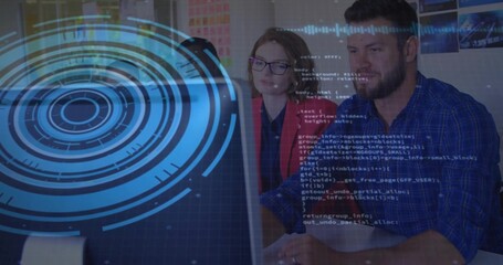 Man and woman in red blazer reviewing code on monitor at office desk, with data overlay