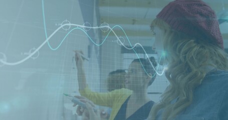 Collaborating office team writing with green marker on whiteboard wall, with digital graph overlay © vectorfusionart