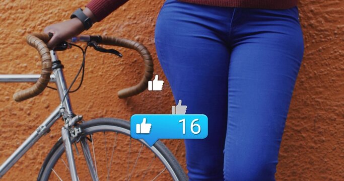 Posing woman at orange wall holding drop handlebars of bike with thumbs-up notification showing 16