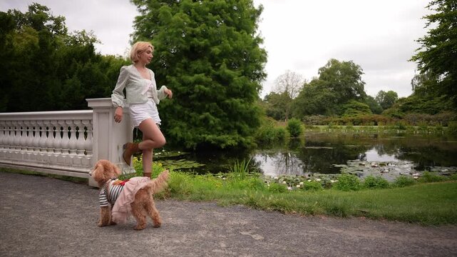 Young blonde short-haired woman and her cute dog resting in nature