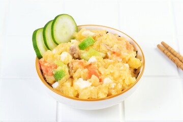 Minimalist food photo of Japanese potato salad with cucumber slices served in a white bowl on clean white background. Perfect for restaurant menu, healthy lunch, or food advertising.