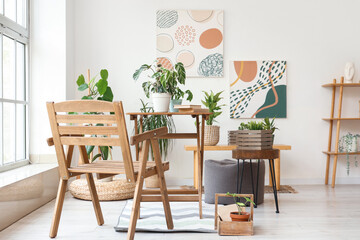 Interior of light room with wooden chair, tables and green plants