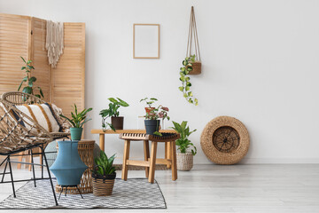 Interior of light room with wicker armchairs, tables and green plants