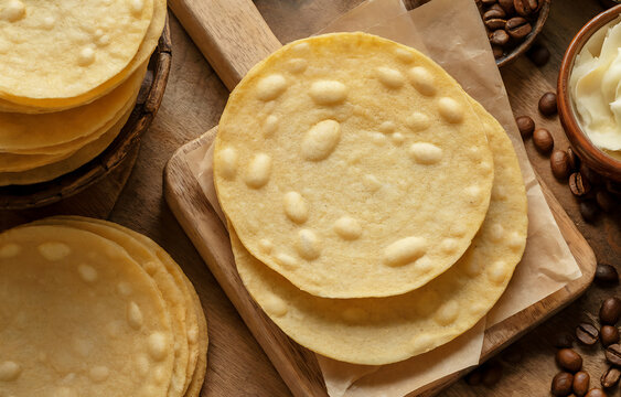 A top-view photograph of traditional Colombian obleas arranged on a rustic wooden surface, showcasing their characteristic round, paper-thin wafer texture. The obleas display a beautiful golden-brown 