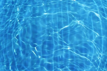 Blue water with ripples on the surface. Defocus blurred transparent blue colored clear calm water surface texture with splashes and bubbles. Water waves with shining pattern texture background.