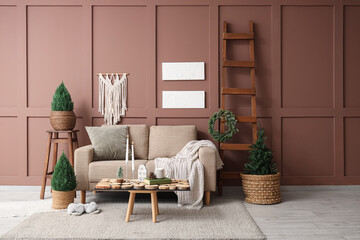 Interior of living room with sofa, Christmas trees and burning candles on table