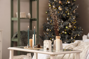 Burning candles with fir cones and willow branches on table in bedroom