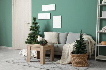 Interior of living room with Christmas trees, sofa and burning candles on table
