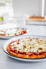 two small margherita pizzas with olives on bigger plates, portion control concept