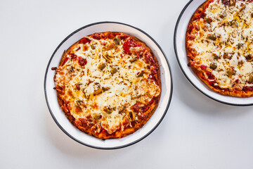 two small margherita pizzas with olives on bigger plates, portion control concept
