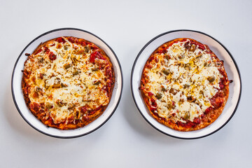 two small margherita pizzas with olives on bigger plates, portion control concept