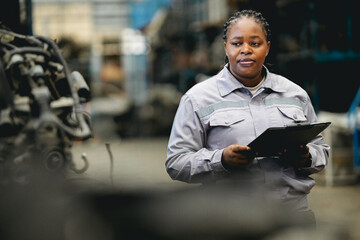 Female technician check used car damaged engine block at scrapyard warehouse recycle area part....