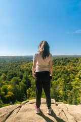 Naklejka premium Peaceful moment of woman admiring panoramic forest and lake view in Algonquin Park.