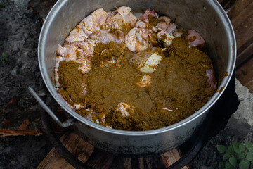 overhead view of chopped thanksgiving turkey with marinade in a large pot, a large pot of seasoned poultry being cooked using firewood