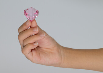 Child's hand holding a large pink plastic diamond gem