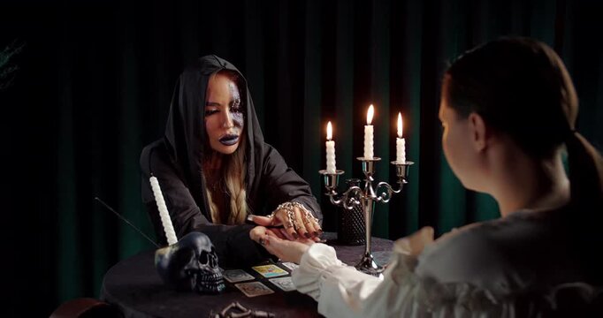 Witch reading client's palm in candlelit fortune telling session