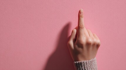 Woman s hand with index finger raised and crossed fingers gesture against a soft pink textured bac