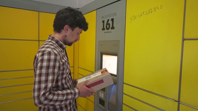 Yellow self-service postal terminal. Man sending parcel. Parcel pick up point, contactless self service post terminal, parcel delivery. Man putting box to parcel machine. Deposit for package storage