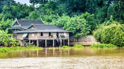 Obraz premium Reflections of Nature: A Serene River House Amidst Lush Green Trees and Stunning Architecture in a Picturesque Landscape