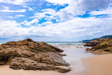 Rocky beach with rocks waves turquoise water in Patong Thailand.