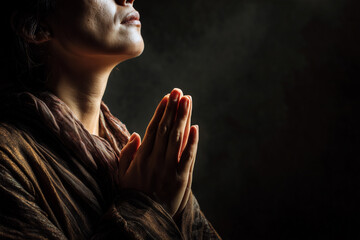 Woman praying in darkness with hopeful expression