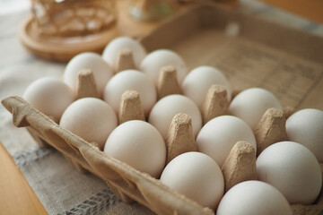 Fresh eggs in a carton on a wooden table in the kitchen