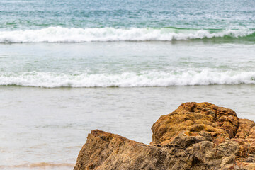 Rocky beach with rocks waves turquoise water in Patong Thailand.