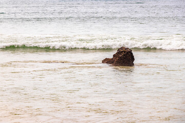 Fototapeta premium Rocky beach with rocks waves turquoise water in Patong Thailand.