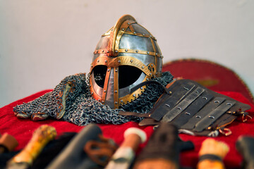 A highly detailed view of medieval ornaments. Featuring antique style, knives, a helmet, Norse symbols, accessories, irons, and a scabbard. Medieval knight's clothing and accessories.