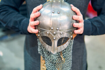 A medieval warrior's helmet shown from the hands. A highly detailed metal helmet with its chainmail...