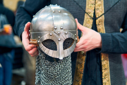 A medieval warrior's helmet shown from the hands. A highly detailed metal helmet with its chainmail and very well maintained. A medieval warrior's helmeted hands.