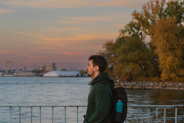 Man standing by the waterfront at sunset enjoying the view