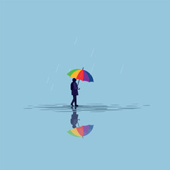 Person walking with a colorful umbrella in the rain, reflected in a puddle.