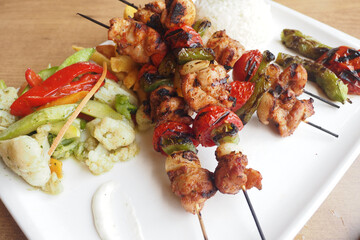 Grilled chicken skewers served with rice and vegetables