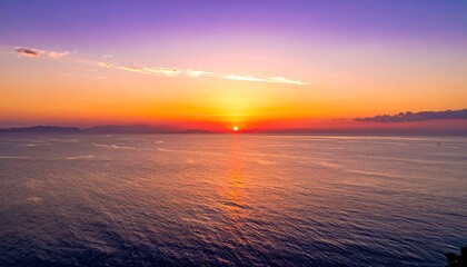 Vibrant sunset over sparkling ocean water with purple and orange sky and distant land silhouette peaceful seascape reflection