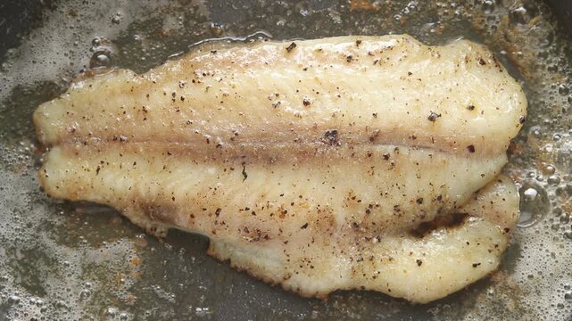 Pan-frying pangasius dory fish fillet on a hot pan. Top view shot