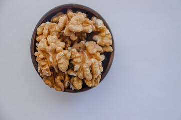 Walnut without shell in wooden bowl on light background
